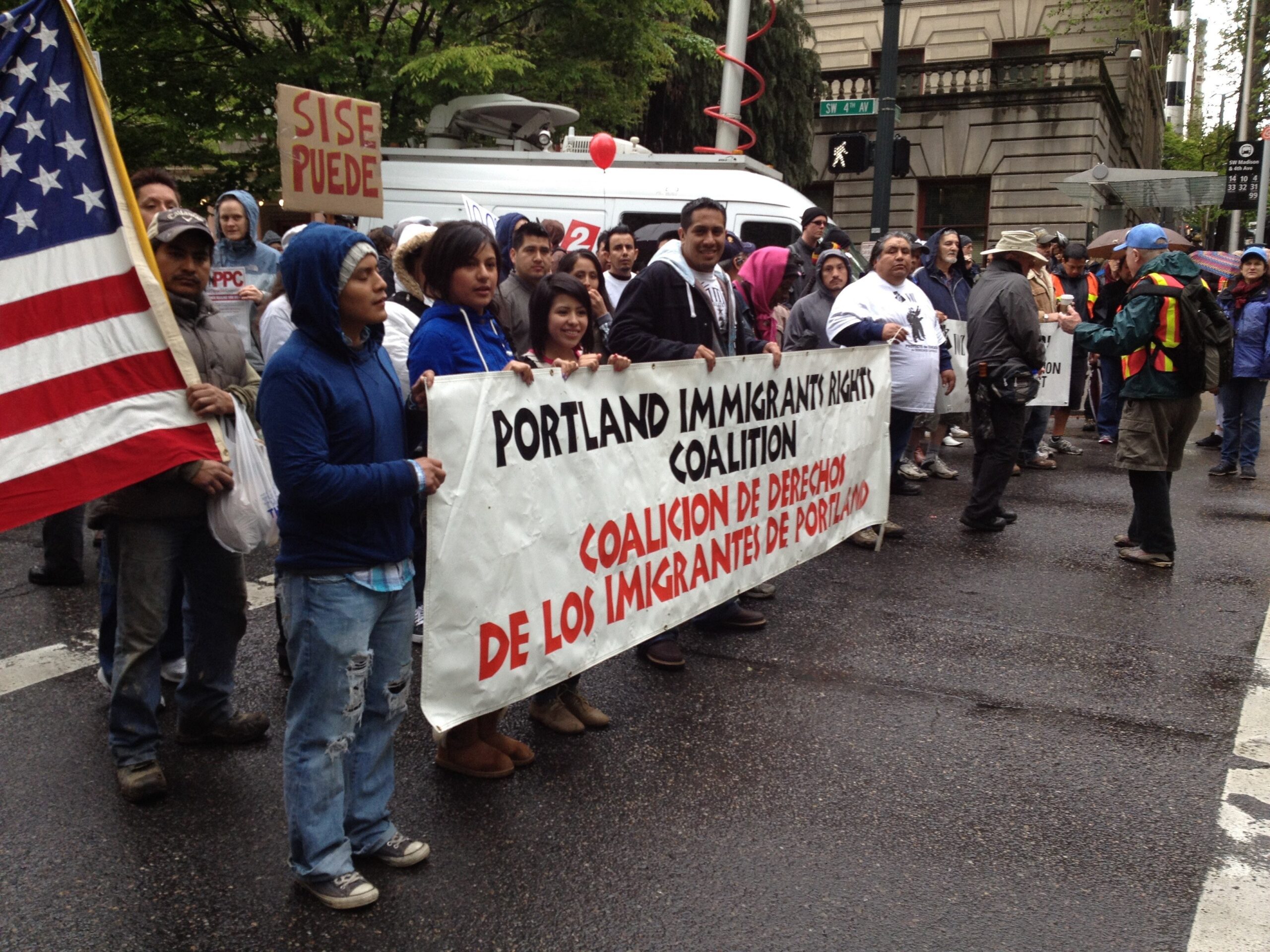 At the front of a May Day protest march, people holding Portland Immigration Coalition banner.