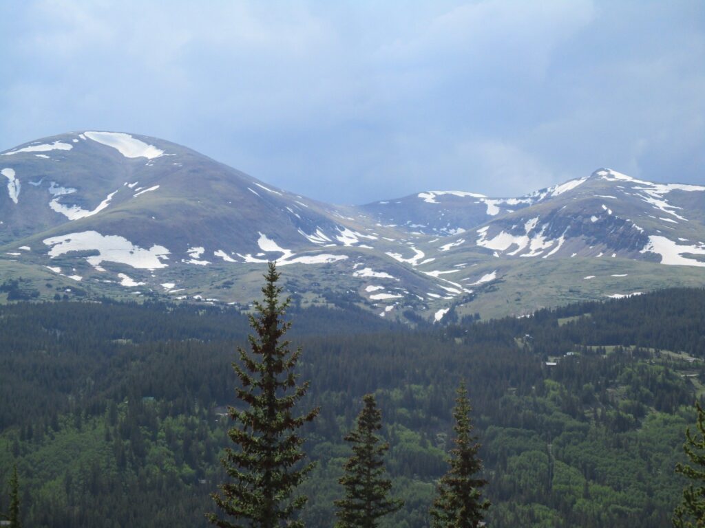Rocky Mountain peaks with snowfields. The sky is grey with the threat of rain.
