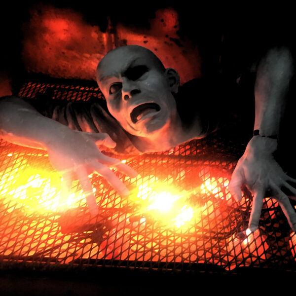 A photo of a sculpture which depicts a man up to his neck in a flaming bar-b-que pit.